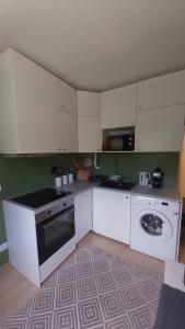 a kitchen with white cabinets and a washing machine at New Life Apartment in Latschach ober dem Faakersee