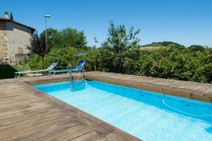 einen Pool mit einer Terrasse und 2 Stühlen in der Unterkunft Antica Casa del Glicine in Poggibonsi