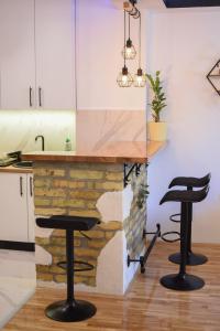 a kitchen with two bar stools in front of a fireplace at Garden Apartment - Oaza u centru grada in Novi Sad