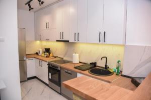 a kitchen with white cabinets and a sink at Garden Apartment - Oaza u centru grada in Novi Sad