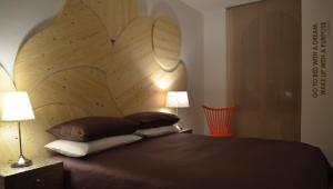 Schlafzimmer mit einem Kopfteil aus Holz und Kissen auf einem Bett in der Unterkunft Angelina Urban Lodge in Tolentino