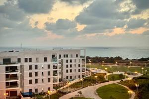 uma vista para um edifício com o oceano ao fundo em Yamba יםבה באכזיב- פנטהאוז חדש ומפנק em Nahariya