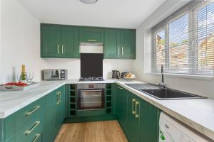 una cocina con armarios verdes y fregadero en Olympic House en Kettering