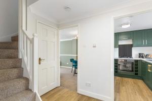 una cocina y escaleras con armarios verdes y una puerta en Olympic House en Kettering