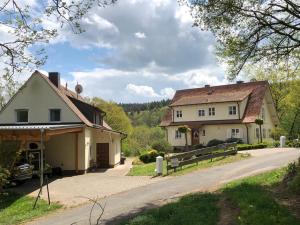 ein großes weißes Haus mit einem Tor und einer Einfahrt in der Unterkunft Ferienwohnung am Rohrbacherhof Sabine Rück in Barackenhöfe