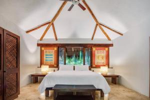 una camera con un letto bianco e due tavoli di The Explorean Kohunlich - All Inclusive a Ruinas Kohunlích