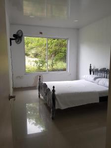 um quarto com uma cama grande e uma janela em Villa Gabriela em Agua de Dios