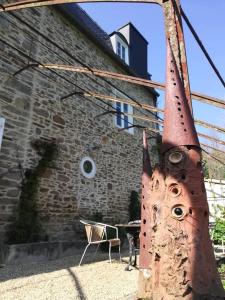 um objecto enferrujado com olhos e uma cadeira em frente a um edifício em Domaine des Papeteries em Plounevez-Moëdec