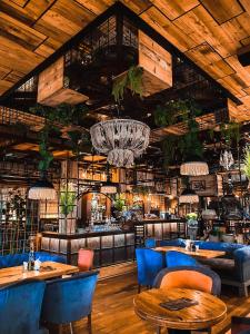 a restaurant with wooden ceilings and blue chairs and tables at Hotel Coandi in Arad