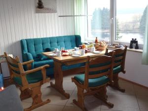 a table with chairs and a blue couch in a room at Haus Seefrieden in Clausthal-Zellerfeld