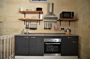 a kitchen with black cabinets and a stove top oven at Città Cospicua suites in Cospicua