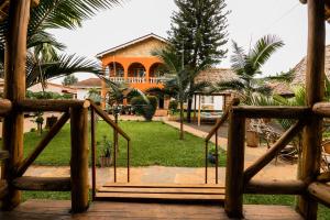 a wooden bridge leading to a house with palm trees at Villa Poa in Arusha