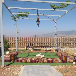a picnic table under a pergola in front of a building at Dar Gerasa chalets The THREE Palm in Jerash