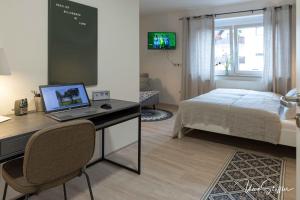 a bedroom with a desk with a laptop and a bed at Sali Homes - GaesteHaus Lamm Obersulm in Obersulm