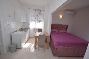 a small bedroom with a purple bed and a table at Subotic S apartmani in Risan