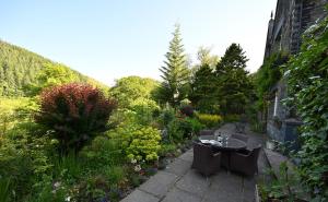 einen Garten mit einem Tisch, Stühlen und Blumen in der Unterkunft The Old Vicarage B&B, Corris in Machynlleth
