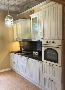 a kitchen with white cabinets and a microwave at Rüütli 1 - sea view apartment in Haapsalu Old Town in Haapsalu