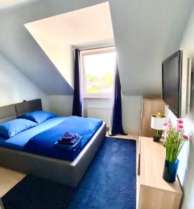 a bedroom with a blue bed and a window at Lake View Ostróda Luxury Apartment in Ostróda