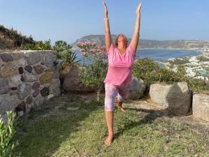 a woman jumping in the air with her hands in the air at Panorama Studios in Kefalos