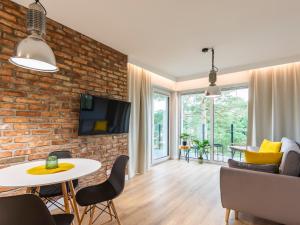 a living room with a brick wall and a table and chairs at VacationClub – Sosnowa 4 Apartament 34 in Mielno