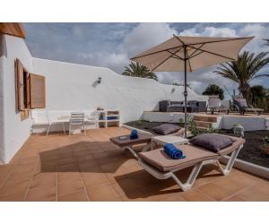 un patio con 2 tumbonas y una sombrilla en Puerto Chico Y, en Playa Blanca