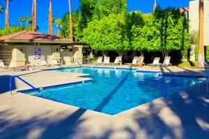 a large swimming pool with chairs and trees at Condo Casa Verde in Palm Springs