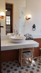 a bathroom with a sink and a large mirror at Chácara das Lendas e Canções in Passa Quatro