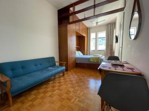 a living room with a blue couch and a bedroom at Studio Buckingham Palace in Teresópolis