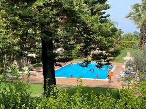 een groot zwembad met mensen in een resort bij Agriturismo Villa Luca in SantʼAgata di Militello