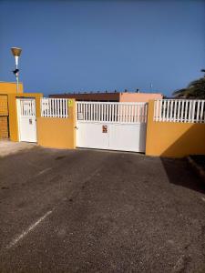 un bâtiment jaune et blanc avec un portail blanc dans l'établissement Fuerteventura, à Costa de Antigua