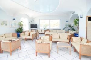 una sala d'attesa con sedie, tavoli e TV di Hotel Felix Terme a Ischia