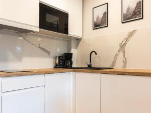 una cocina con armarios blancos y fregadero en VacationClub – Sosnowa 4 Apartament 43 en Mielno