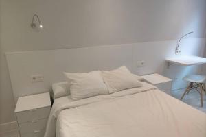 a white bedroom with a bed and a desk at Apartamento recién reformado en Barakaldo in Barakaldo