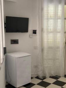 Dieses weiße Zimmer verfügt über einen TV und einen Vorhang. in der Unterkunft Case Vacanze Giovanna in Petrosino