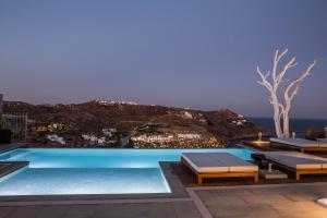 a beach with a pool, chairs, and a balcony overlooking the ocean at Lyo Boutique Hotel Mykonos in Super Paradise Beach