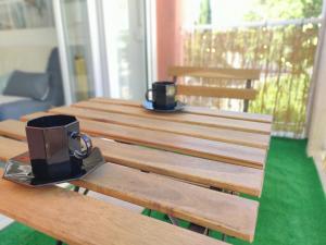 - une table en bois avec deux tasses à café assises dans l'établissement STUDIO LE GALICE avec TERRASSE et PARKING, à Aix-en-Provence