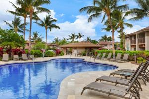 a pool at a resort with chairs and palm trees at Waikoloa Colony Villas 2202 in Waikoloa