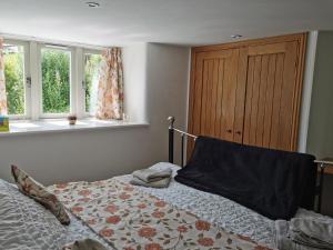 a bedroom with a bed and two windows at Bowbeer Barn in Drewsteignton