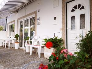 un gruppo di sedie bianche e fiori su un patio di Casa do Rio a Termas de São Pedro do Sul