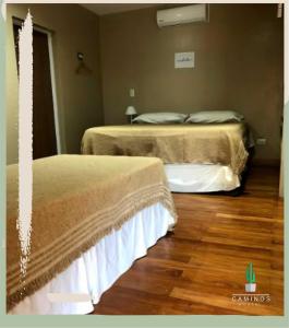 two beds in a room with wooden floors at Caminos Hostal in San Salvador de Jujuy