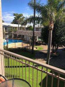 a balcony of a house with a pool and palm trees at Tranquility at Mandurah Apartments in Mandurah