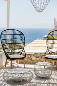 two chairs and a table on a patio with the ocean at Amyth of Mykonos Super Paradise in Super Paradise Beach