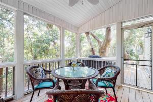 a screened in porch with a table and chairs at Chateau Relaxo in Edisto Beach