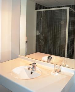 a white sink sitting under a mirror in a bathroom at L'Albatros in Morlaix
