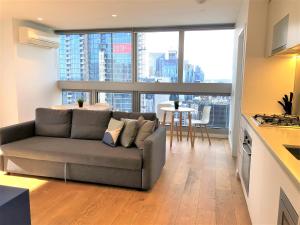 メルボルンにあるReadySet Apartments on Rose Laneのソファと大きな窓のあるリビングルーム