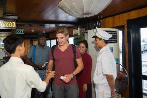 a group of people standing around a man in a ship at Syrena Cruises in Ha Long