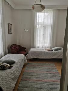 2 camas en una habitación con ventana y alfombra en Utajärven Pappila Olden Vicarage en Utajärvi
