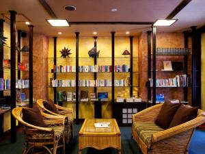 a living room with a couch and chairs and book shelves at Coco Garden Resort Okinawa in Uruma