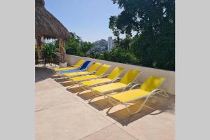 Condominio familiar y exclusivo Tres Mares في أكابولكو: صف من الكراسي الصفراء والزرقاء على الفناء