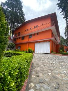 un edificio naranja con un garaje blanco delante de él en Hotel Posada Castillo Panteon Ingles, en Mineral del Monte